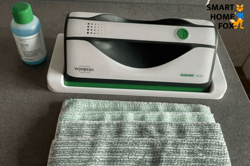 Vorwerk Kobold VG Fensterreinigungsgerät liegt samt Reinigungsmittel und 2 Wischtüchern auf dem Tisch
